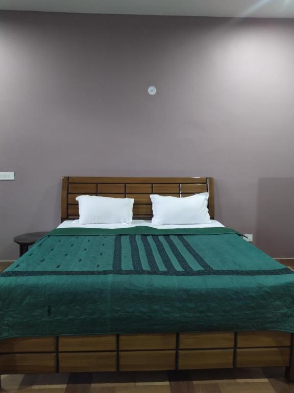 a bed with a green comforter and two pillows at The pine view Orchard homestay in Rāmgarh
