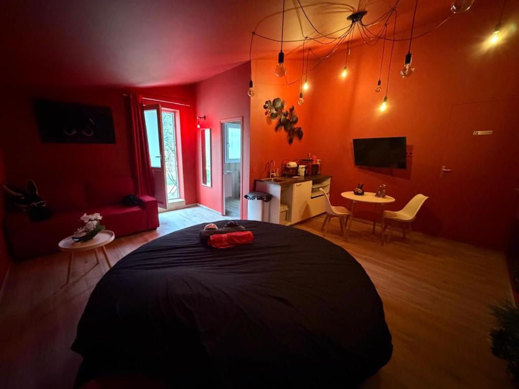 a bedroom with red walls and a bed and a table at Love Room- Jacuzzi XXL- Climatisé- Table massage Accessoires in LʼEscarène