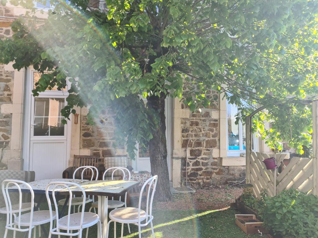 a table and chairs under a tree on a patio at L'Art de l'Être in Saint-Vincent-de-Reins