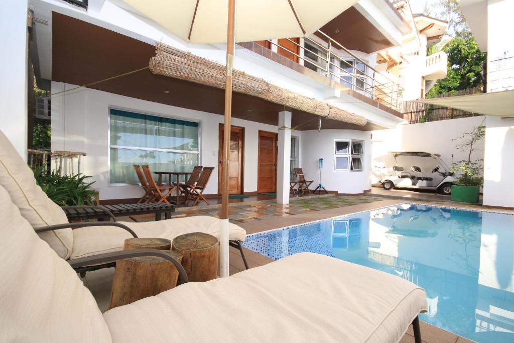 a house with a swimming pool with chairs and an umbrella at Bluewaves Westcliff Villa in Boracay
