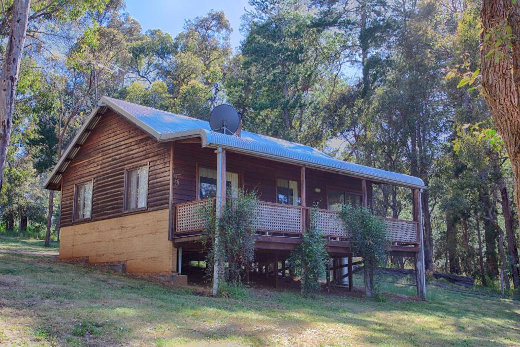 a large wooden house with a porch and a roof at Balinga Cottages in Balingup