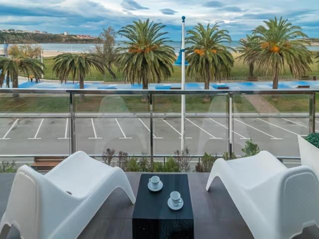 a balcony with two white chairs and a tennis court at Alojamientos Marte apartamento a pie de playa y garaje in Suances
