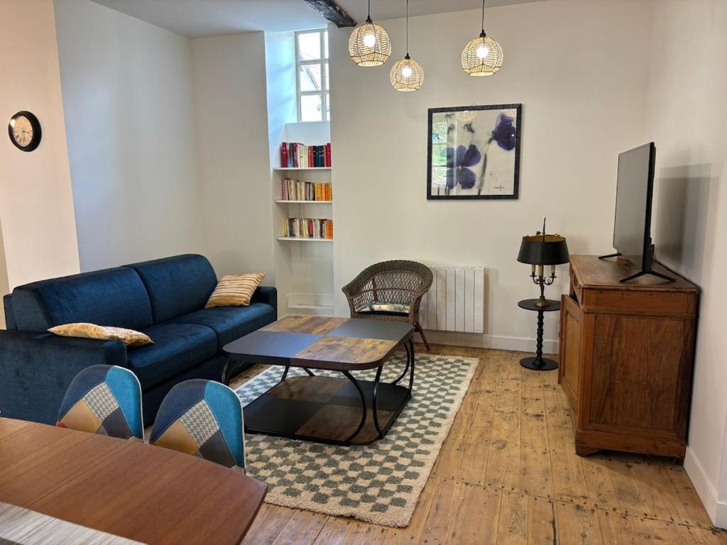 a living room with a blue couch and a tv at gite 4 le refuge in Aubeterre-sur-Dronne