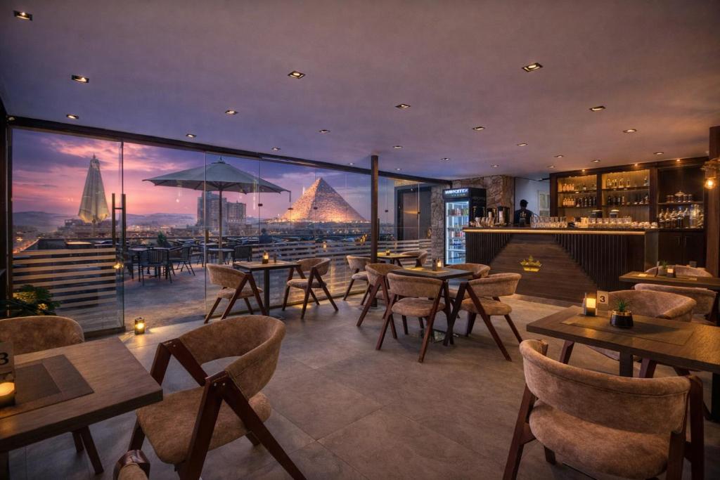 a restaurant with tables and chairs and a view of the pyramids at TAJ Suites Pyramids View Hotel in Cairo