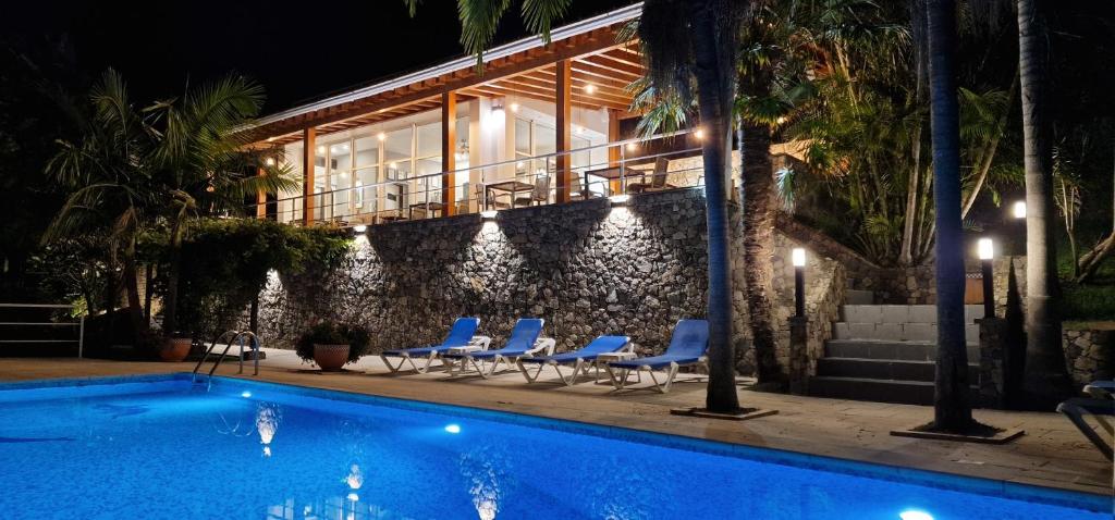 a house with chairs and a swimming pool at night at Quinta do Mar in Água de Pau