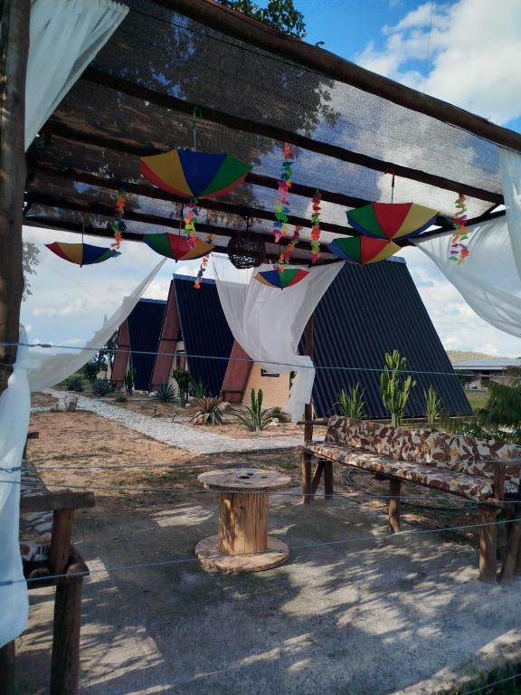 a picnic shelter with a table and umbrellas at Chalés Vale da Luma in Cavalcante