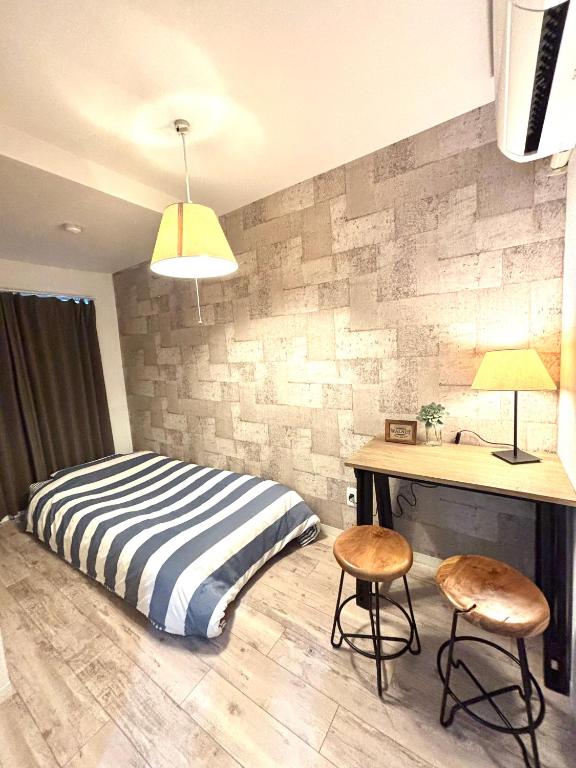 a bedroom with a bed and a desk and two stools at Guest House Re-worth Yabacho1 302 in Nagoya