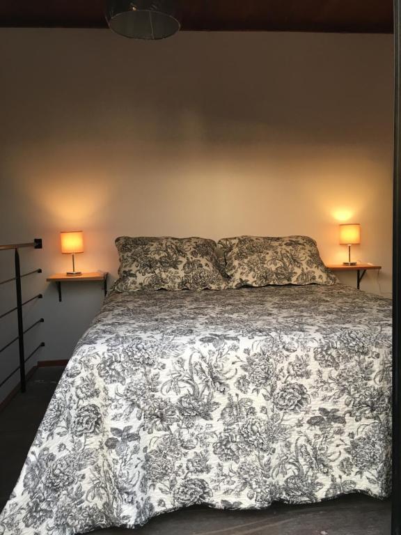 a bed with a black and white comforter and two lamps at Pretas in Punta Del Diablo