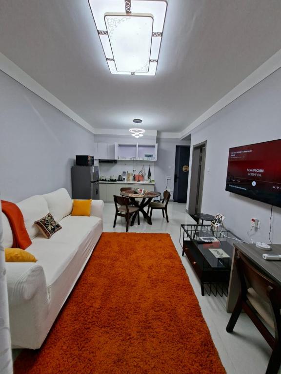 a living room with a white couch with an orange rug at Haven Place 254-near JKIA,SGR with Self-Check in & Free Parking in Nairobi