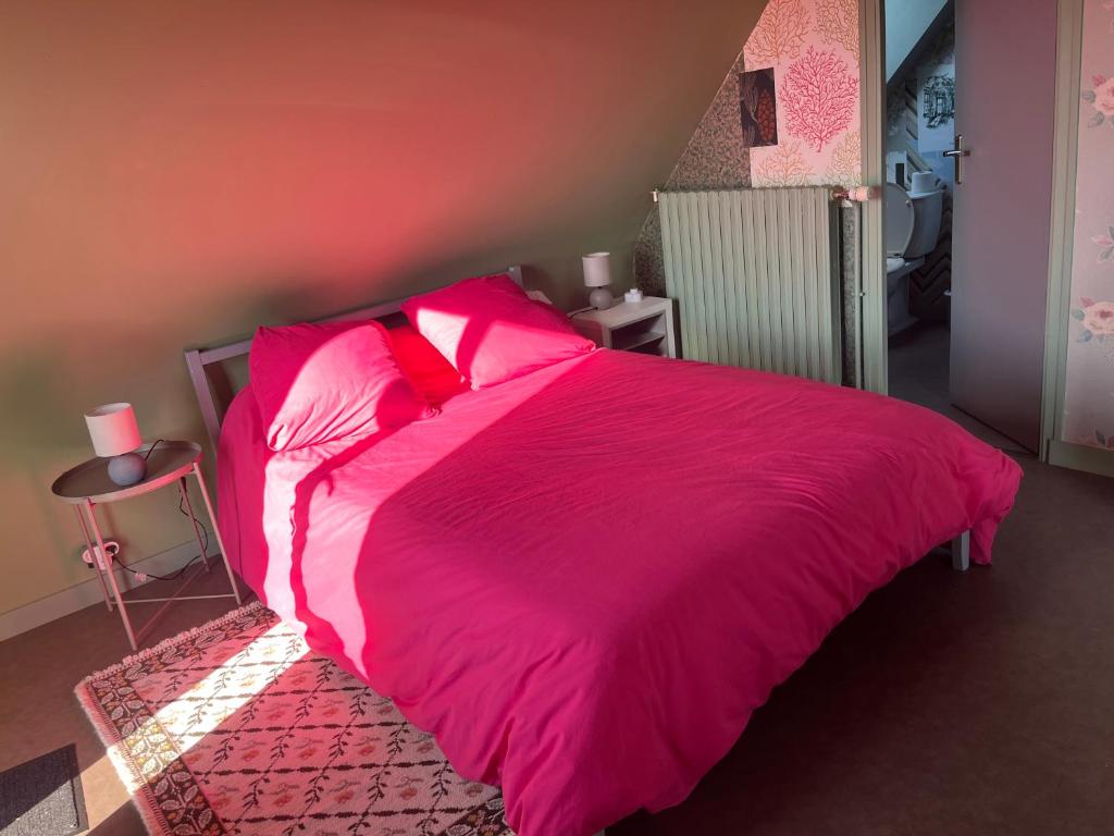 a large pink bed with pink sheets and pillows at Escapade de charme à Questembert in Questembert