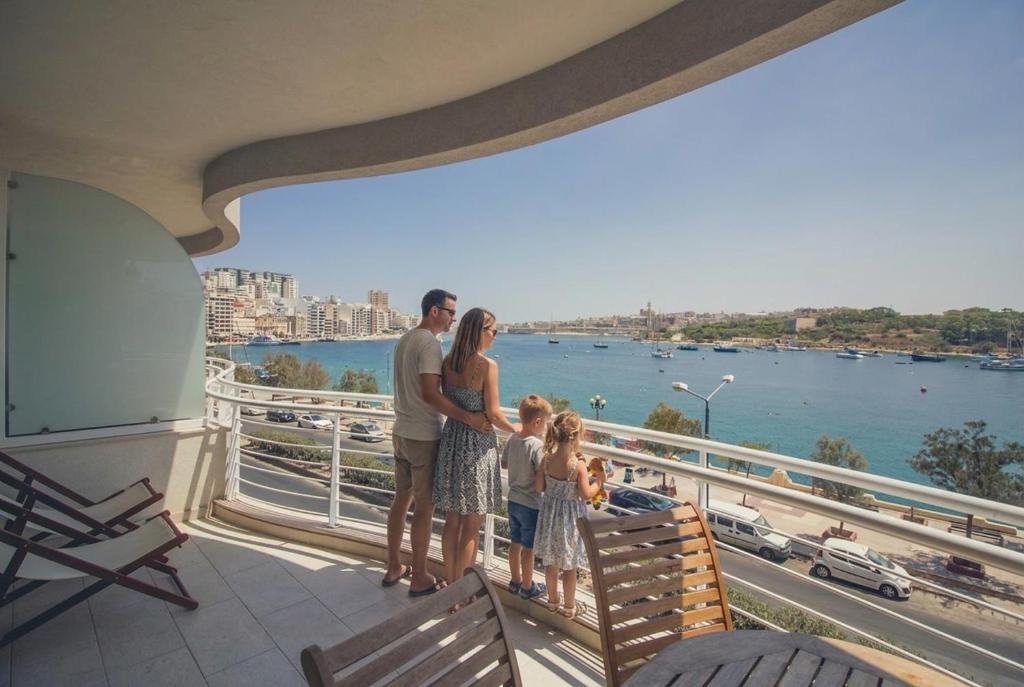 a family standing on the balcony of a building at The Strand Waterfront Apartment with 3 Bedrooms, 4 Bathrooms, Private Garage in Sliema