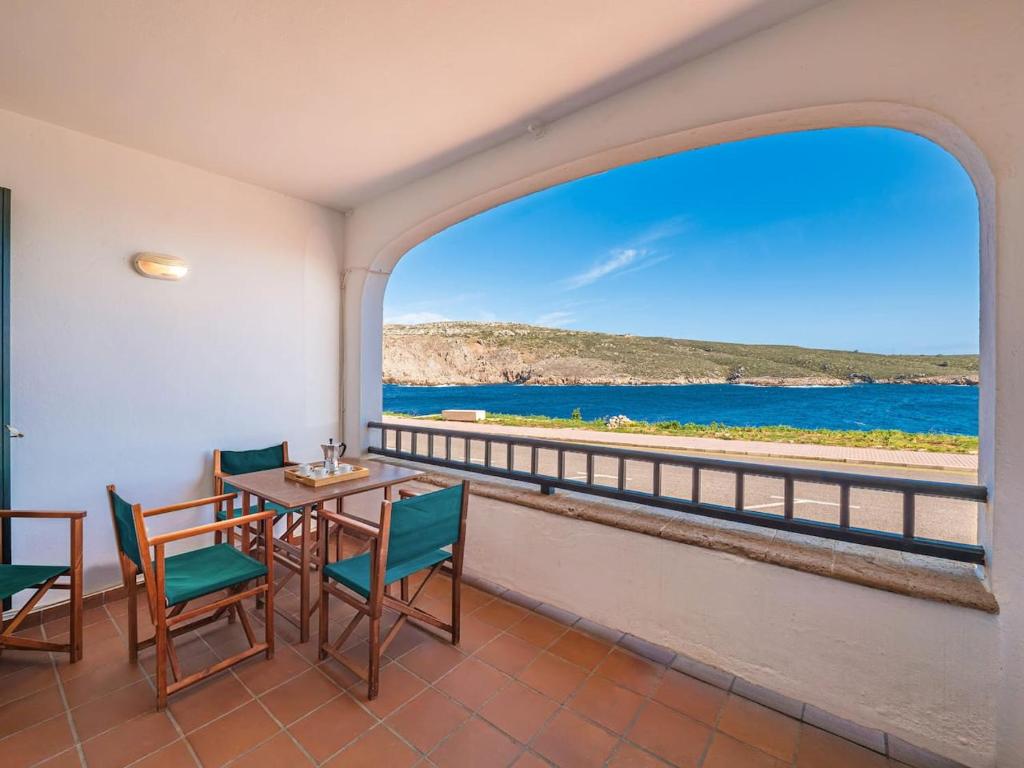 a balcony with a table and chairs and a view of the ocean at Els Tamarells Apartment by 3VILLAS in Fornells