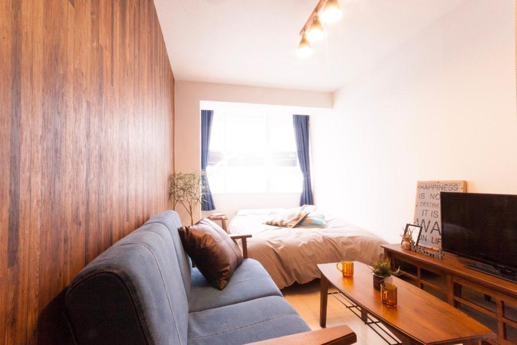 a living room with a couch and a bed at Guest House Re-worth Yabacho1 401 in Nagoya