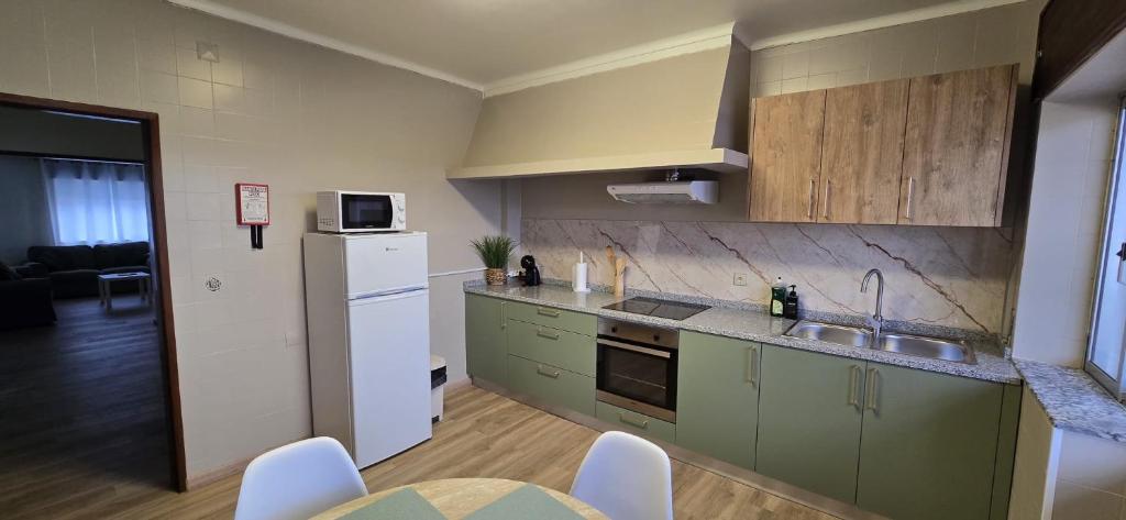 a kitchen with green cabinets and a white refrigerator at Apartamento Vila Melgaço in Melgaço