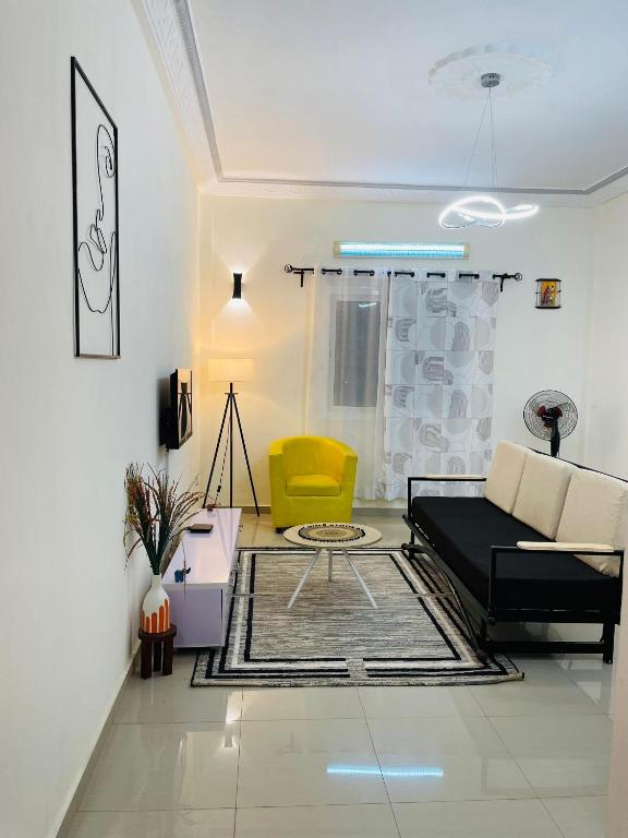 a living room with a black couch and a yellow chair at Les Résidences CICA in Ouidah