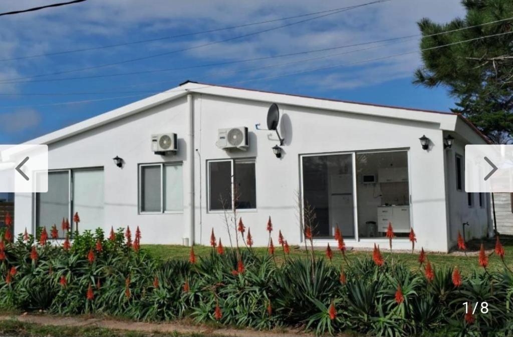 a white house with red flowers in front of it at Rodolfo in La Paloma