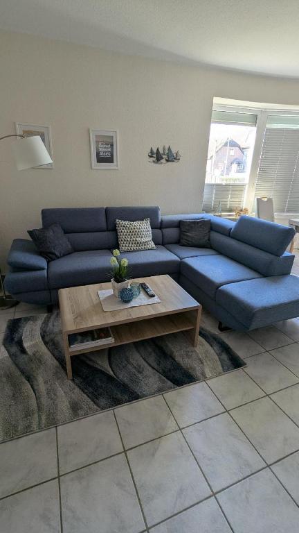 a living room with a blue couch and a coffee table at Käptn Seebär in Friedrichskoog-Spitze