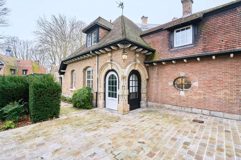 a brick house with a large driveway in front of it at Le Petit Broc in Wasquehal