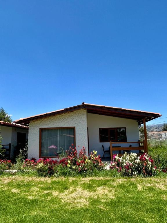 a house with a bench and flowers in front of it at Casa del abuelo Lodge in Cajamarca