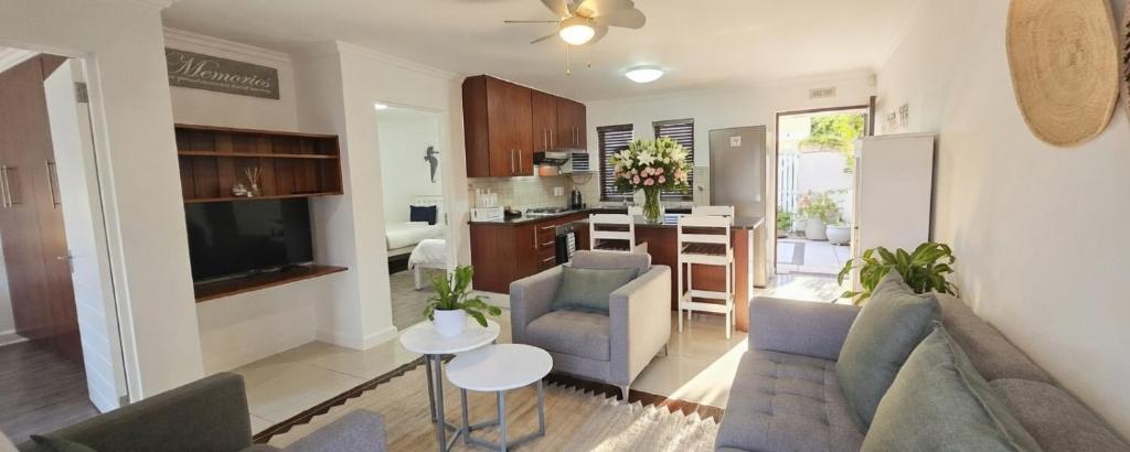 a living room with a couch and chairs and a kitchen at Sandstone - 2 x Bedroom Apartment! in Knysna