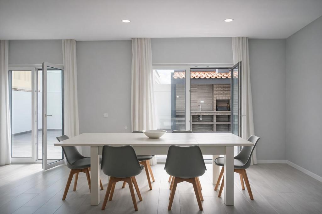 a white dining room with a table and chairs at Refúgio de Ferrel in Ferrel