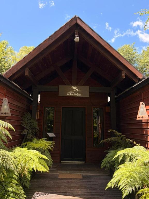 a wooden building with a door with a sign on it at Estero El Claro Hotel y Cabañas in Pucón