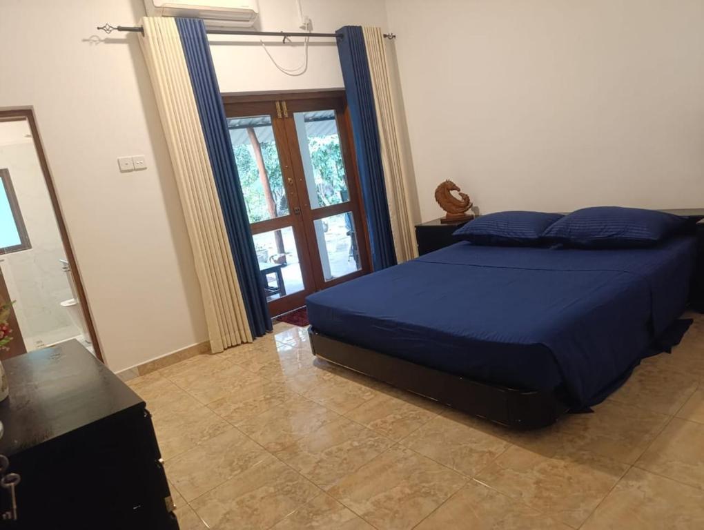 a bedroom with a blue bed and a window at Golden Leaf house in Weligama