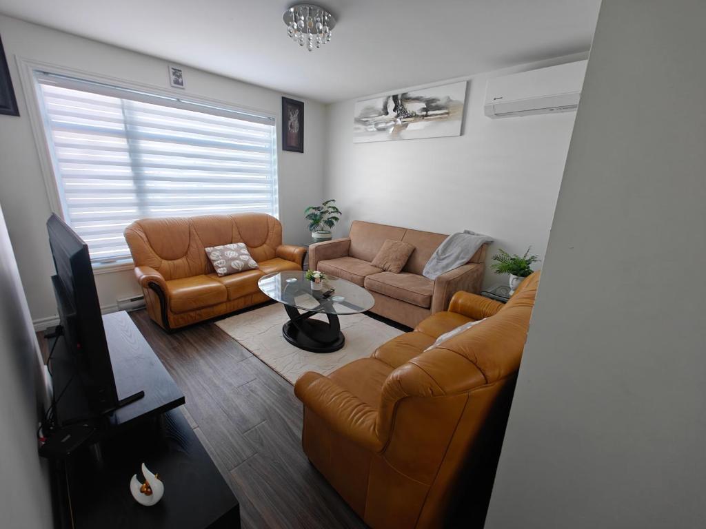 a living room with two couches and a tv at Appartement sur deux niveaux in Quebec City