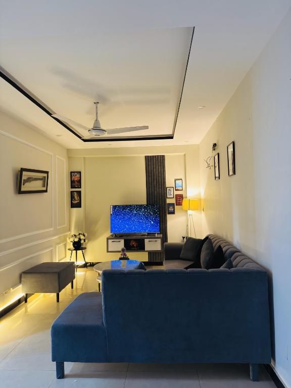 a living room with a blue couch and a television at Stay Homie - 1BHK, Near ISB Airport, Self Check-In, Secure in Islamabad