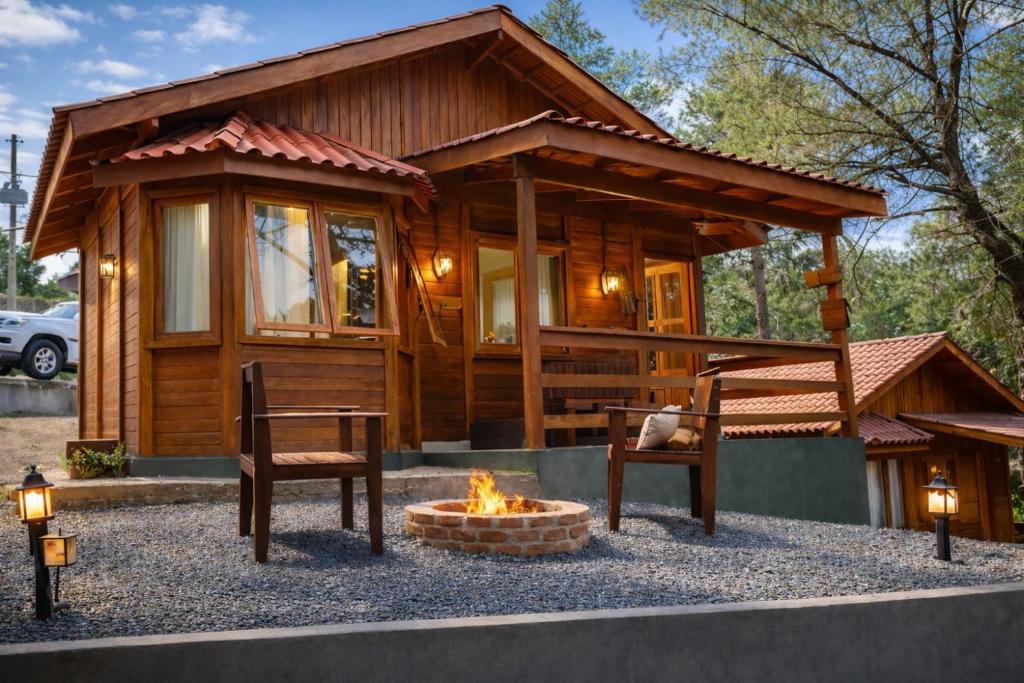 a log cabin with two chairs and a fire pit at Cabanas Green Valley in Monte Verde