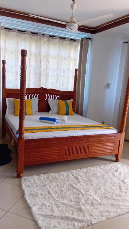 a bedroom with a large wooden bed in front of a window at Palm Comfort Apartment in Bamburi