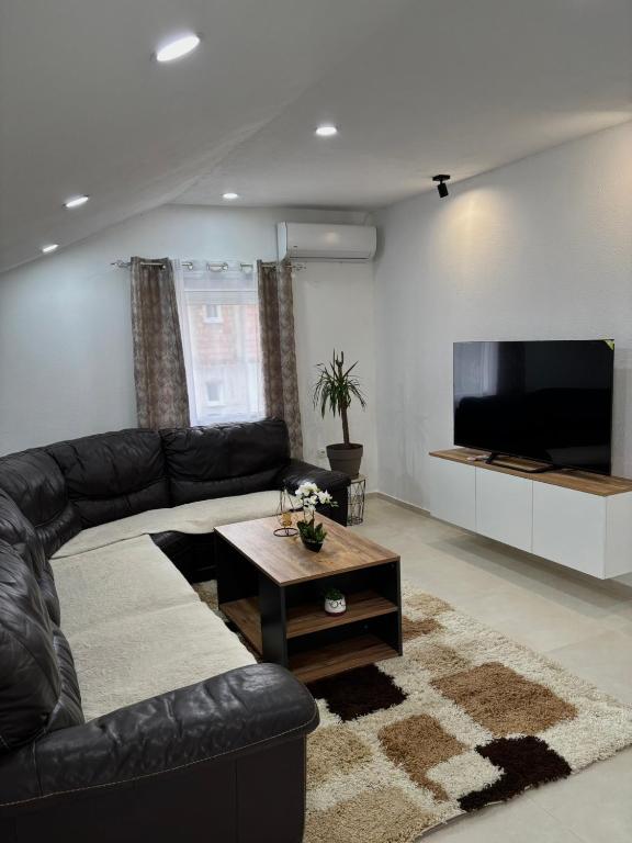 a living room with a black leather couch and a flat screen tv at Bulatović in Ðuranovići