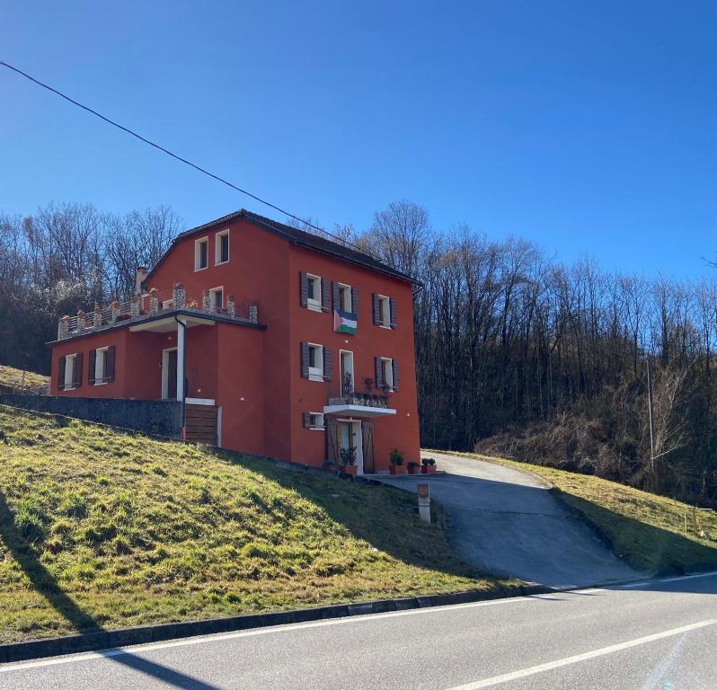 a red building on a hill next to a road at La Libellula Rossa in Puos dʼAlpago