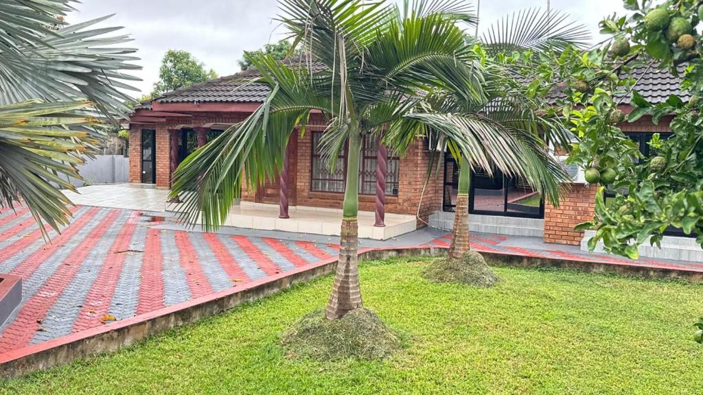 a house with two palm trees in front of it at Mercy Guesthouse in Thohoyandou
