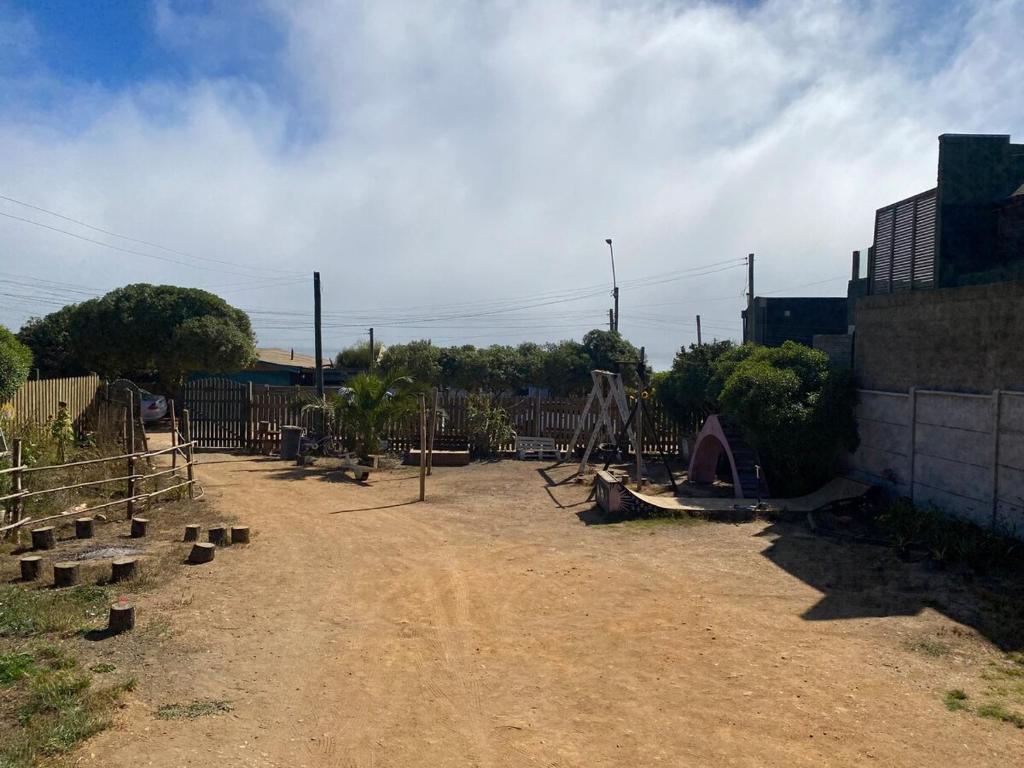 a dirt yard with a playground and a fence at Cabaña a pasos del mar in El Cerrillo
