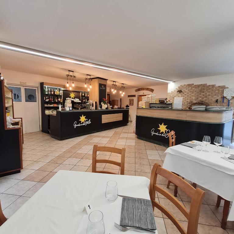 a restaurant with white tables and chairs and a bar at Hotel Giardino del Sole in Savona