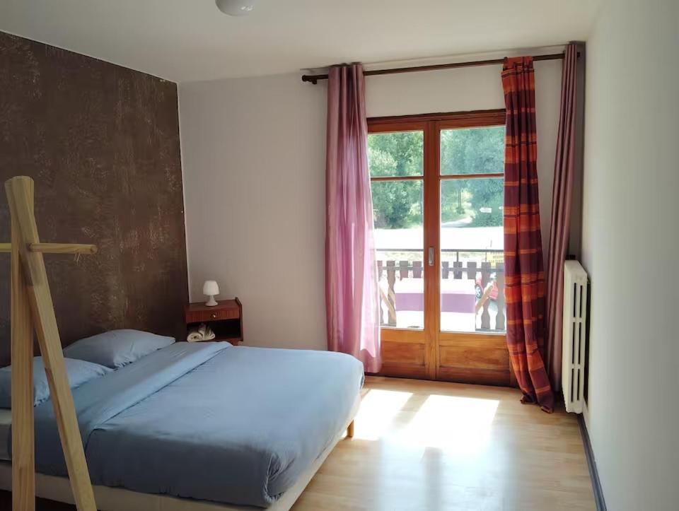 a bedroom with a bed and a large window at Chambre La Charolaise in Aubessagne