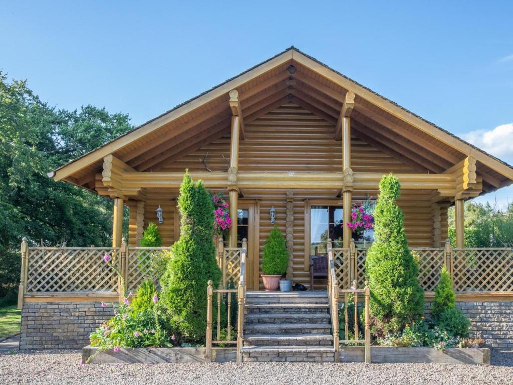 a log cabin with a porch and stairs in front at 3 Bed in Dunsyre oc-lk15m in Walston