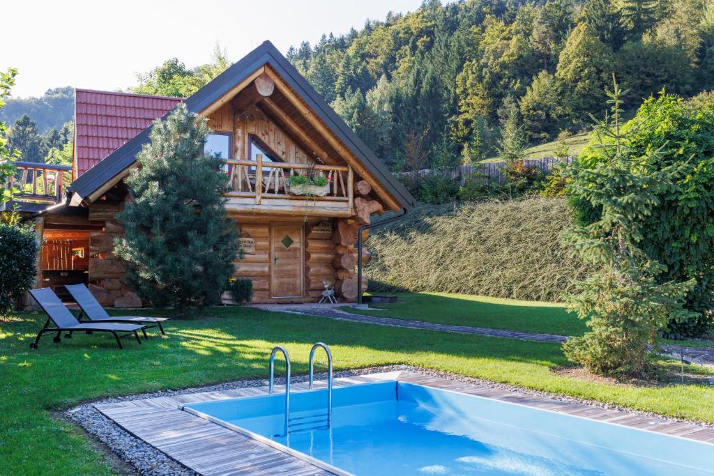a log cabin with a pool in the yard at Forest Glade Cottage - Koča na jasi in Rečica ob Savinji