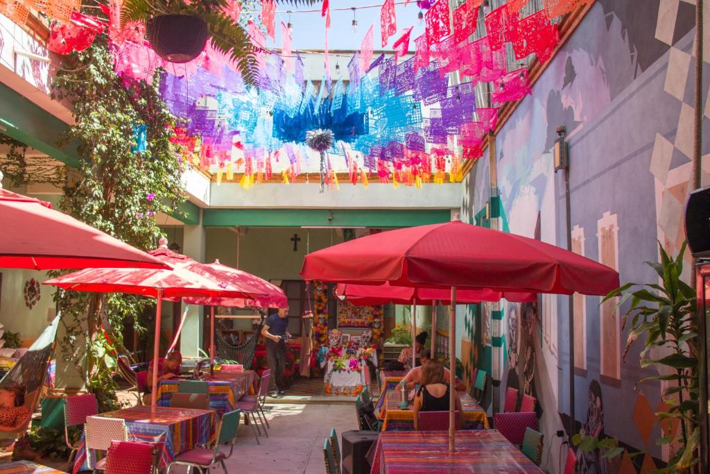a patio with tables and red umbrellas in a building at Hierba De Conejo Hostel in Oaxaca City