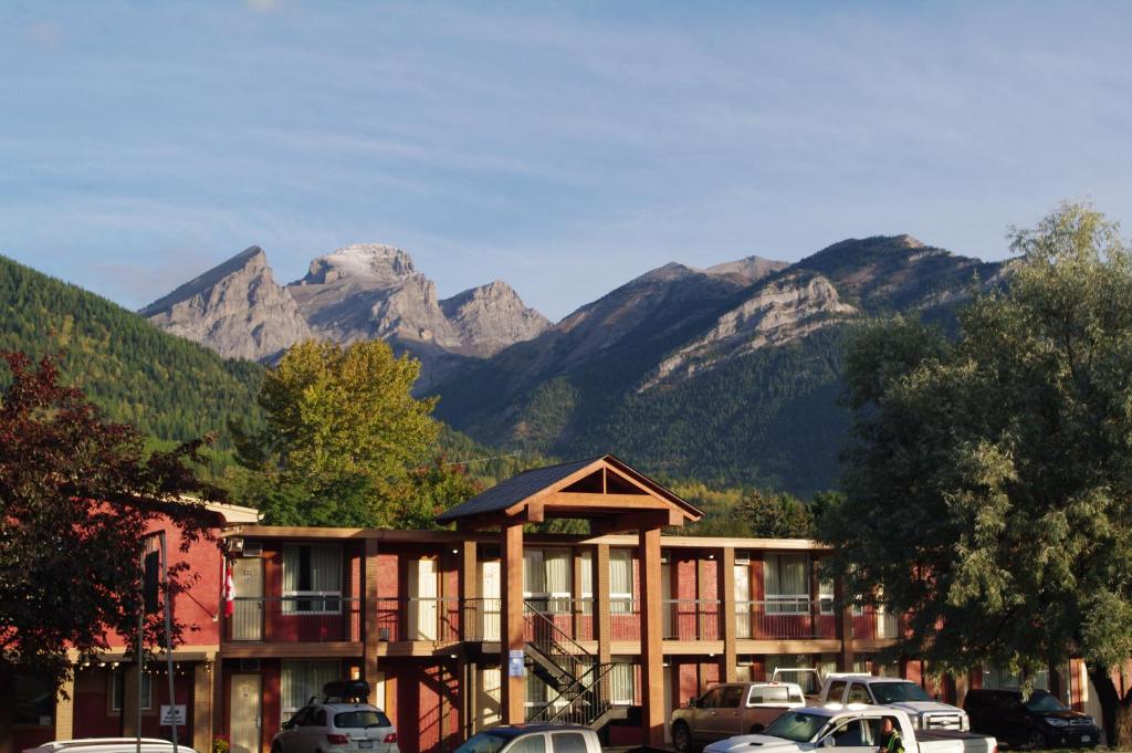 a hotel with cars parked in a parking lot with mountains at EasyStay Inn & Suites Fernie in Fernie