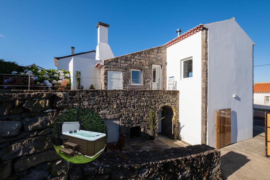a house with a stone wall and a sink at Casa do Simão, Açores - Now with hot tub! in Nordeste