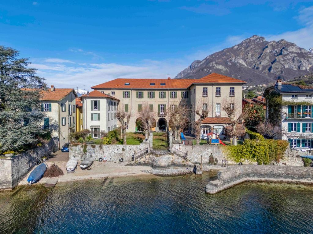 a house on the water with mountains in the background at Foresteria Monastero B&B in Mandello del Lario