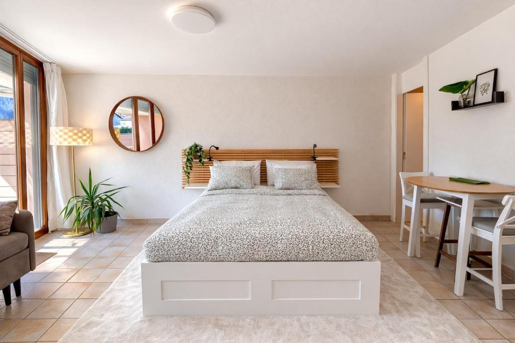 a bedroom with a white bed and a table at Bright studio Martigny - 30 min from Verbier - free parking in Martigny-Ville