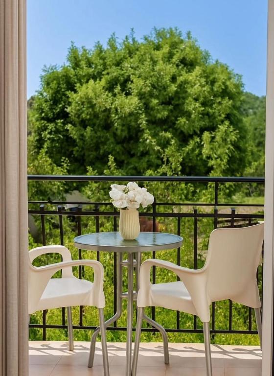 a table with two chairs and a vase of flowers on a balcony at Dionysios Studios in Skala