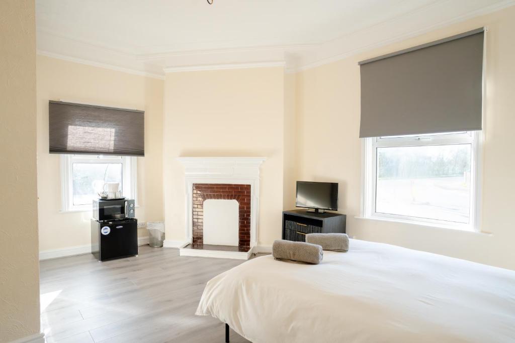 a white bedroom with a bed and a fireplace at Chestnut Lodge Bed & Go in Eastleigh