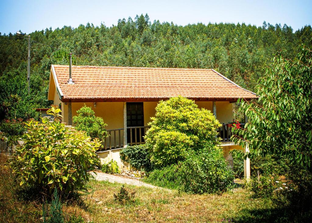 a small yellow house with a balcony and trees at Barbeito Country House in Paraíso