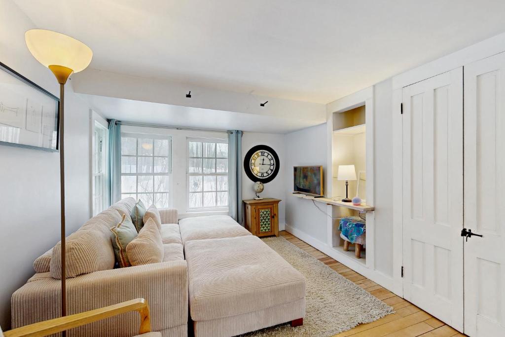 a living room with a couch and a clock on the wall at The Hilltop - West Wing in Waterbury