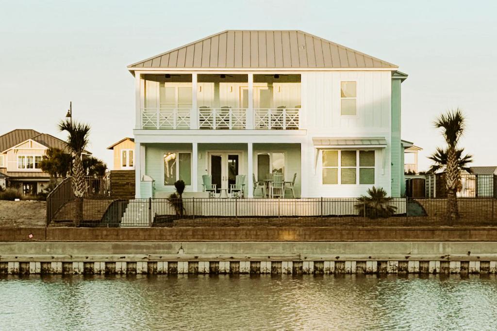 a white house on the shore of a body of water at Tortuga Palms in Rockport