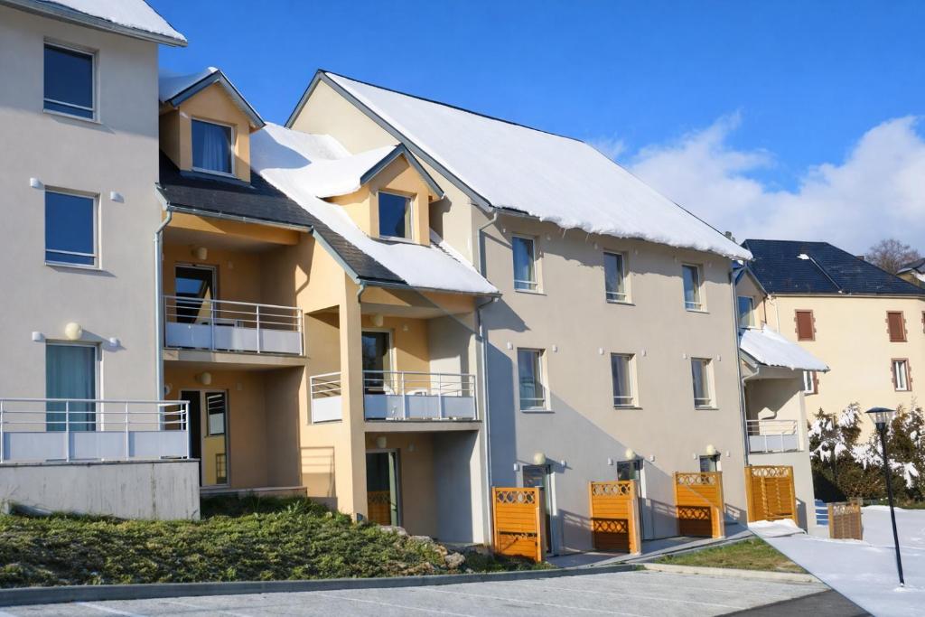 an apartment building with snow on the roof at Les Balcons du Sancy - Résidence de Tourisme in Picherande